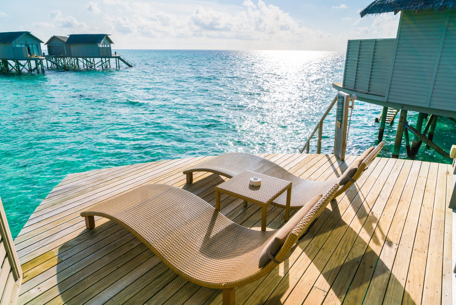 Two deck chairs on the wooden floor in water villa sunset time ,